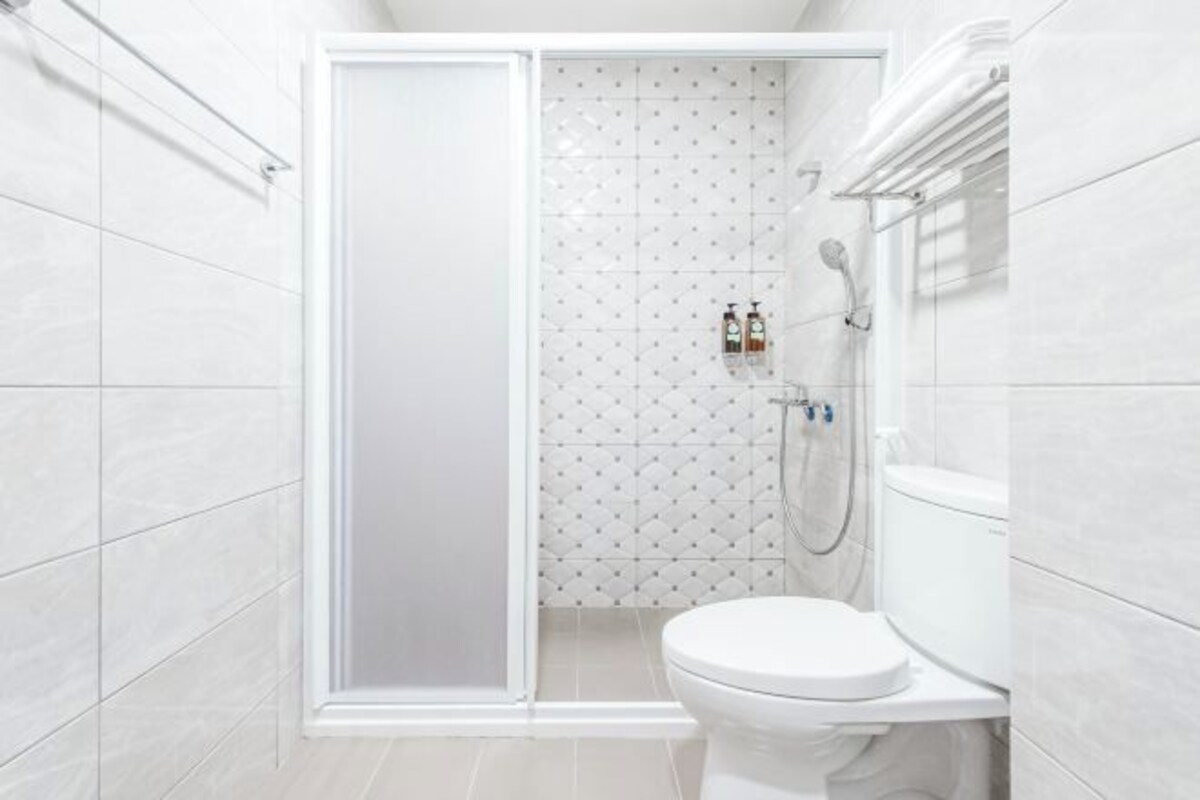 A modern bathroom with a shower, toilet, and tiled walls.