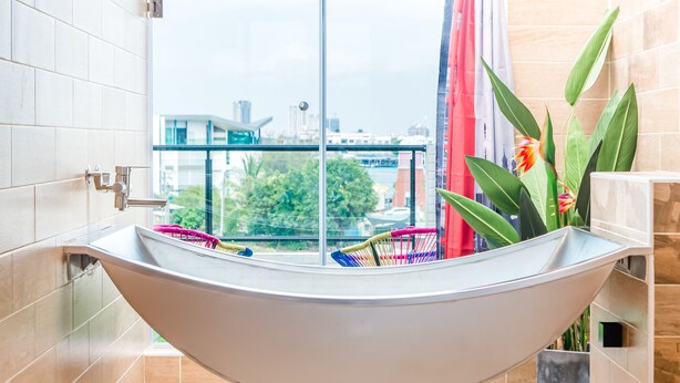 A modern bathroom with a freestanding bathtub, a glass shower enclosure, and a view of the cityscape. - Flying Club (Tainan)