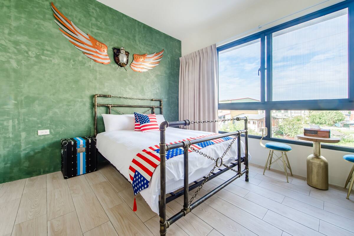 Une chambre d’hôtel avec un lit, une fenêtre donnant sur un paysage agréable, une table et une chaise.