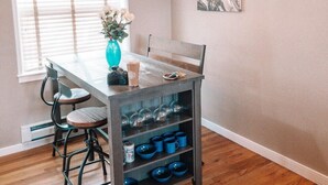 Een eetruimte met een houten tafel, stoelen, een bloevas, een kroonluchter en een schilderij aan de muur.