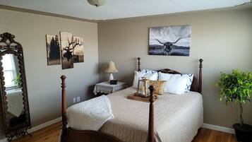 Un dormitorio con una cama con dosel, una mesita de noche con lámpara, un espejo y obras de arte en las paredes.