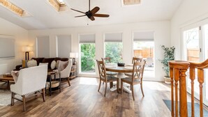 Un grand espace de vie doté d’un ventilateur de plafond, d’une table à manger avec des chaises, d’un canapé et d’une table basse.