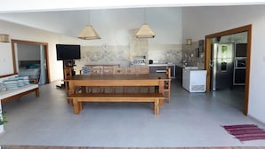 Une cuisine spacieuse avec un coin repas, comprenant une table et des bancs en bois, un four encastré et un réfrigérateur.