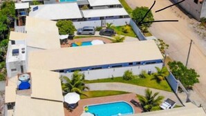 Un complexe hôtelier proposant plusieurs types d’hébergements en style bungalow, une piscine centrale et une vue sur la plage.