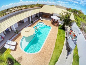 Ein Swimmingpool mit Rutsche, Liegestühlen und einer überdachten Sitzgelegenheit.