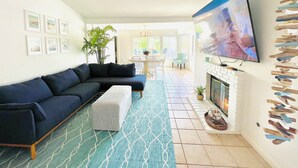 Uma sala de estar moderna com sofá em L, televisão de tela plana na parede e lareira.