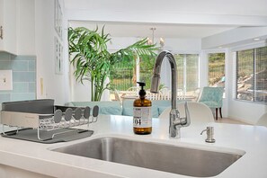 Eine moderne Küche mit Spüle aus Edelstahl, einer Kokosölflasche und einem Wasserkocher.