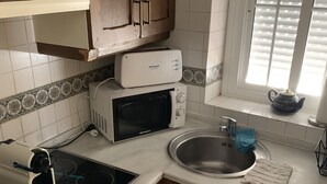 Eine kompakte Küche mit Mikrowelle, Herd, Spüle und Waschmaschine.