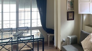 Ein Wohnzimmer mit Glastisch, Stühlen, einer Couch, einer Deckenleuchte und einer Heizung.