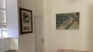 Ein Schlafzimmer mit einem Bett, einem Fenster mit Jalousien, einer Tür und einer Hängeleuchte.
