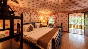 A room with a bed, wooden headboard, a nightstand with a lamp, and a window with curtains. - Jungle Cave Resort (Sawai Madhopur)