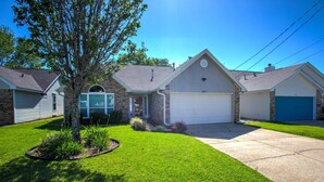 A two-story house with a garage, a well-maintained lawn, and a tree in the front yard. - Month Stays Available | Close to Hurlburt Field, Navarre & Okaloosa | Dogs Ok |Fenced Yard |Foosball (Mary Esther)