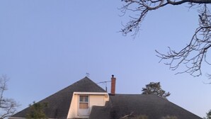 A two-story brick house with a gabled roof, a chimney, and a small porch.