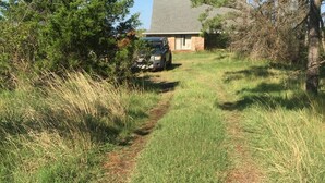 A gravel path leading to a house with a brick exterior and a sloped roof.