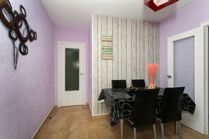 Ein Essbereich mit einem Tisch für vier Personen, einer Wandverkleidung und einer Tür mit Milchglas.