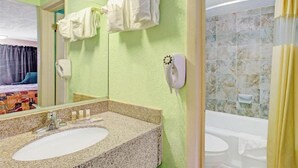 Un baño con lavamanos de granito, cabezal de ducha de mano y zona de ducha con azulejos.