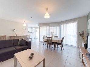 A modern living room with a sofa, a coffee table, and a dining area with a table and chairs.