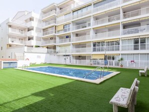 A multi-story hotel with a swimming pool surrounded by artificial grass.