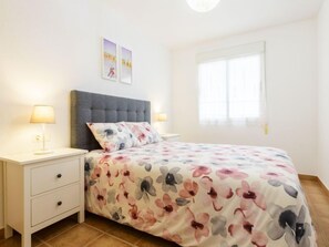 A bedroom with a bed, nightstands, a drawer unit, and a window.