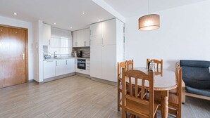 Eine moderne Küche mit weißen Schränken, einem Esstisch mit Stühlen und einem Sofa im Wohnbereich.
