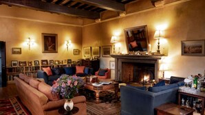 Una sala de estar acogedora con chimenea, asientos cómodos y una estantería llena de libros.