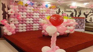 A decorated stage with pink and white balloons, a red carpet, and a backdrop of balloon arrangements. - Hotel Comfort Inn Bl (Bareilly)