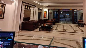 A hotel lobby with a modern ceiling design, leather seating, and a reception area. - Hotel Comfort Inn Bl (Bareilly)