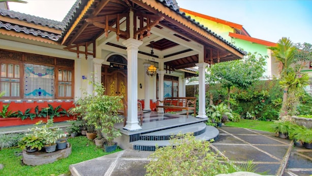 A traditional building with a covered porch, potted plants, and a stone pathway. - Griya Joglo Kaliurang (Ngaglik)