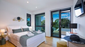 A modern bedroom with a large bed, a desk, and a view of the outdoors.