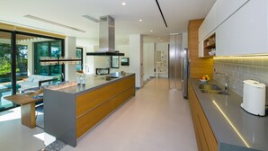 A modern kitchen with a central island, stainless steel appliances, and a large window overlooking a garden.