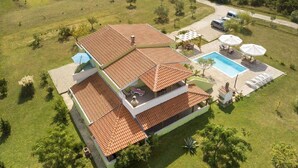A two-story house with a swimming pool, outdoor seating, and a well-maintained lawn. - Adorable apartment with swimming pool and terrace (Ljubač)