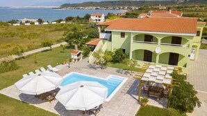 A two-story building with a swimming pool, outdoor seating, and a view of the sea. - Adorable apartment with swimming pool and terrace (Ljubač)