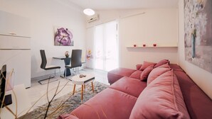 A modern living room with a pink sofa, a small table, a chair, and a painting on the wall. - Adorable apartment with swimming pool and terrace (Ljubač)