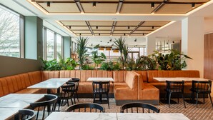 A modern restaurant with leather booths, marble tables, and black chairs.