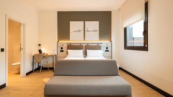 A modern bedroom with a large bed, bedside tables, a desk, and a window.