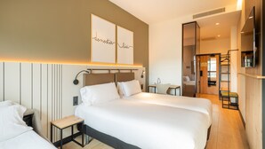 A modern hotel room with two beds, a small table, and a mirror. - Leonardo Hotel San Sebastián (San Sebastián)