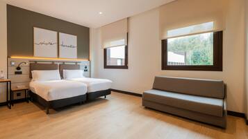 A modern bedroom with a bed, bedside tables, a sofa, and artwork on the wall.