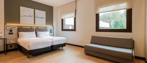 A modern bedroom with a bed, bedside tables, a sofa, and artwork on the wall.
