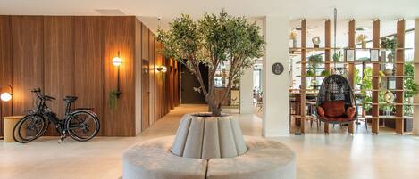 Un intérieur moderne avec un espace salon circulaire, des murs recouverts de panneaux en bois, un fauteuil suspendu et une bibliothèque agrémentée de plantes.
