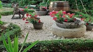 A garden with a statue, potted plants, and a large barrel.