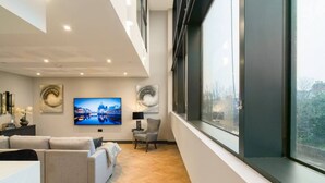 Een moderne woonkamer met een bank, een televisie en een groot raam.