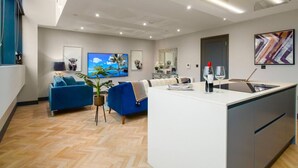 A modern living room with a sofa, a coffee table, and a TV. - Exquisite 2 Bed Duplex Apt | Secure Parking | (Penarth)