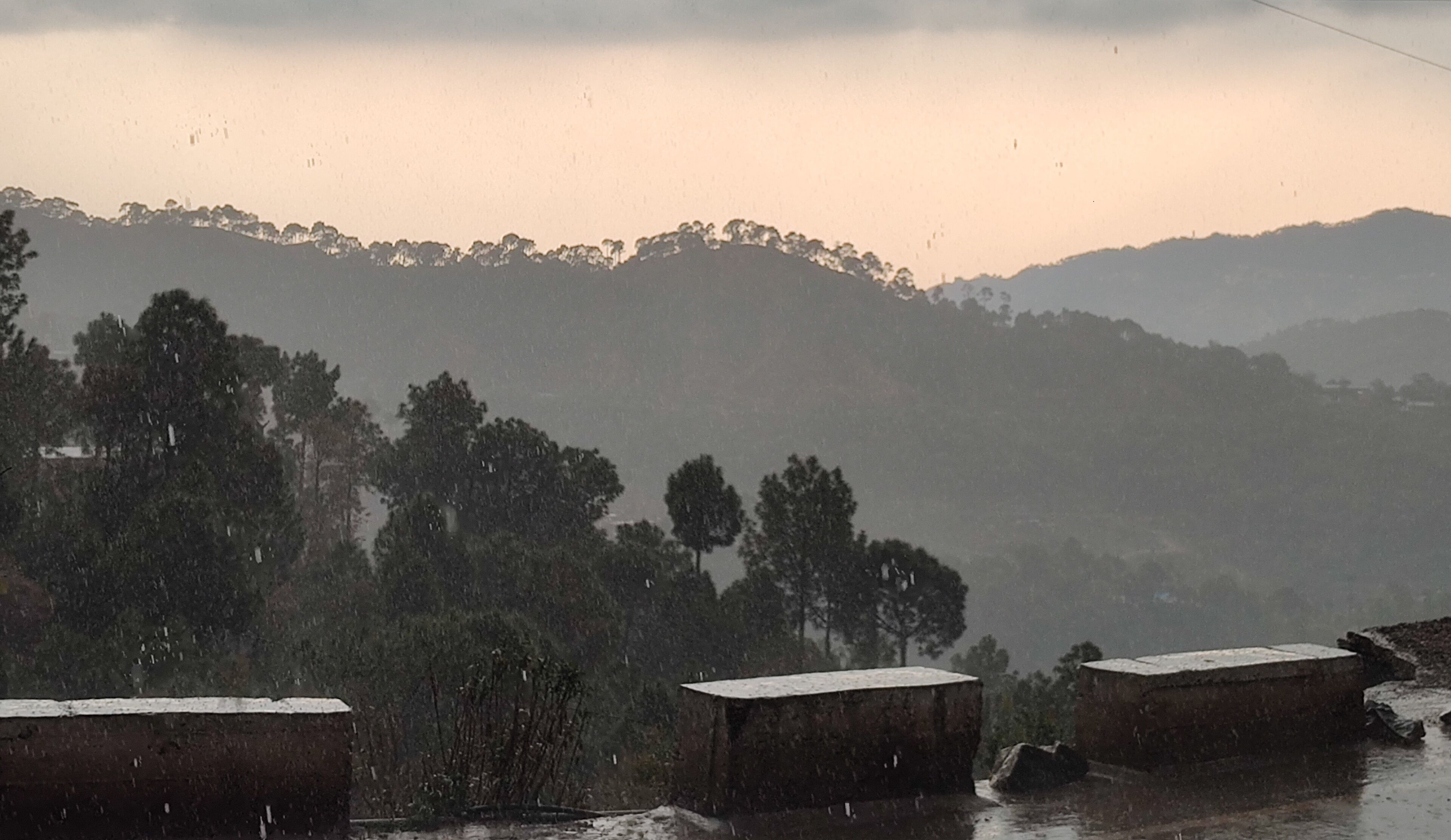 A view of a mountainous landscape with trees and a building in the foreground.