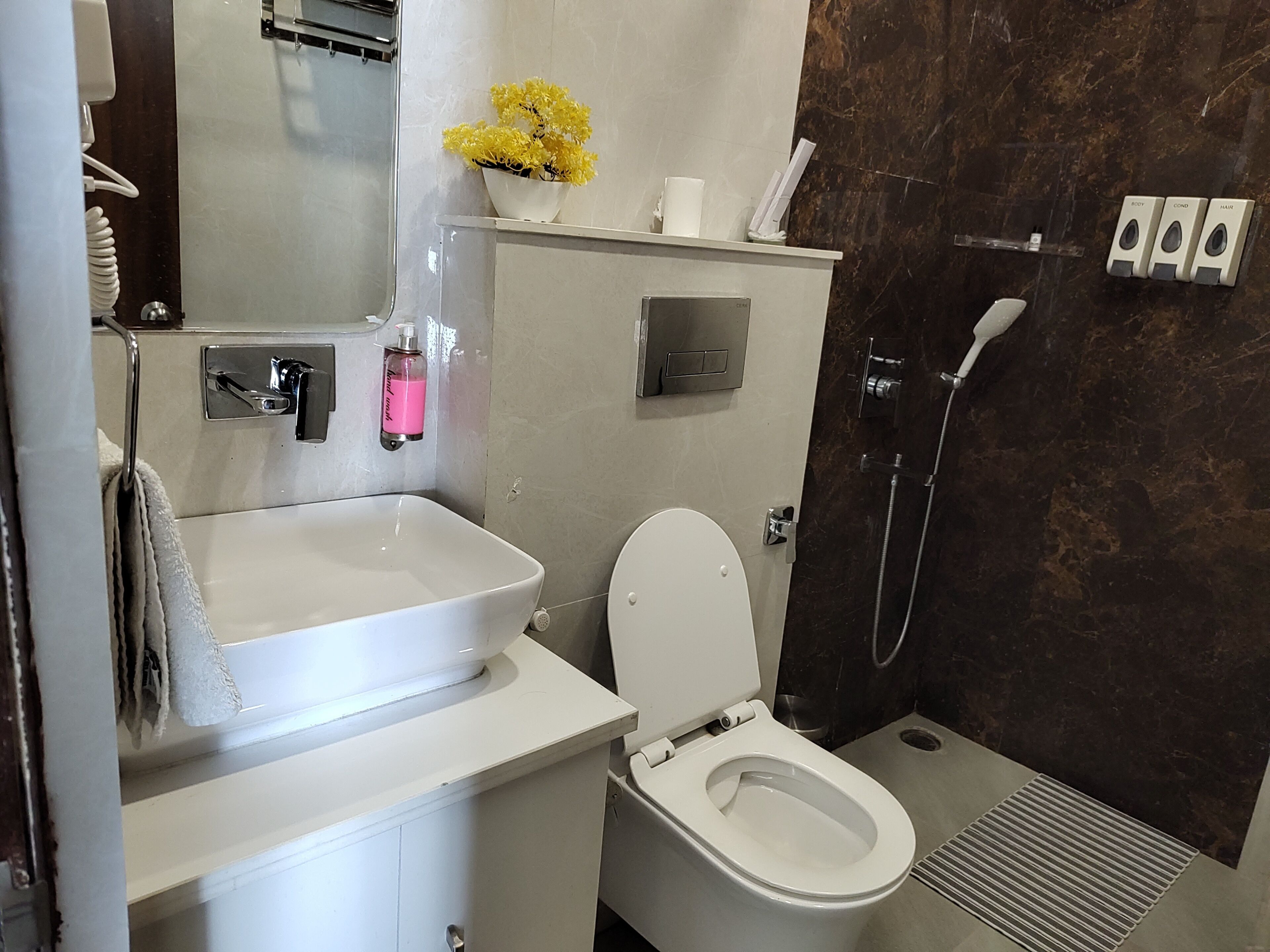 Egy modern fürőszoba fehér mosdókagylóval, WC-vel és zuhanyzóval.