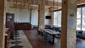 A restaurant with wooden walls, hanging light fixtures, and a checkered floor. Tables are set with plates and cutlery. - Hotel Le Halcyon (Solan)