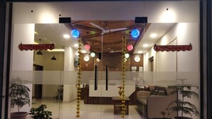 A reception area with a reception desk, a sofa, and potted plants. - Hotel Le Halcyon (Solan)