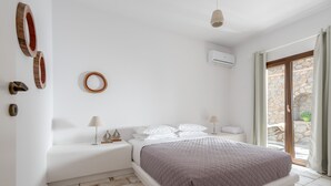 Une chambre à coucher avec un lit, des tables de chevet, une lampe et une vue sur l’extérieur.