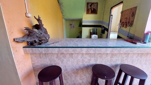 Un espace bar avec un comptoir en verre, deux tabourets, une décoration en bois et un calendrier accroché au mur.