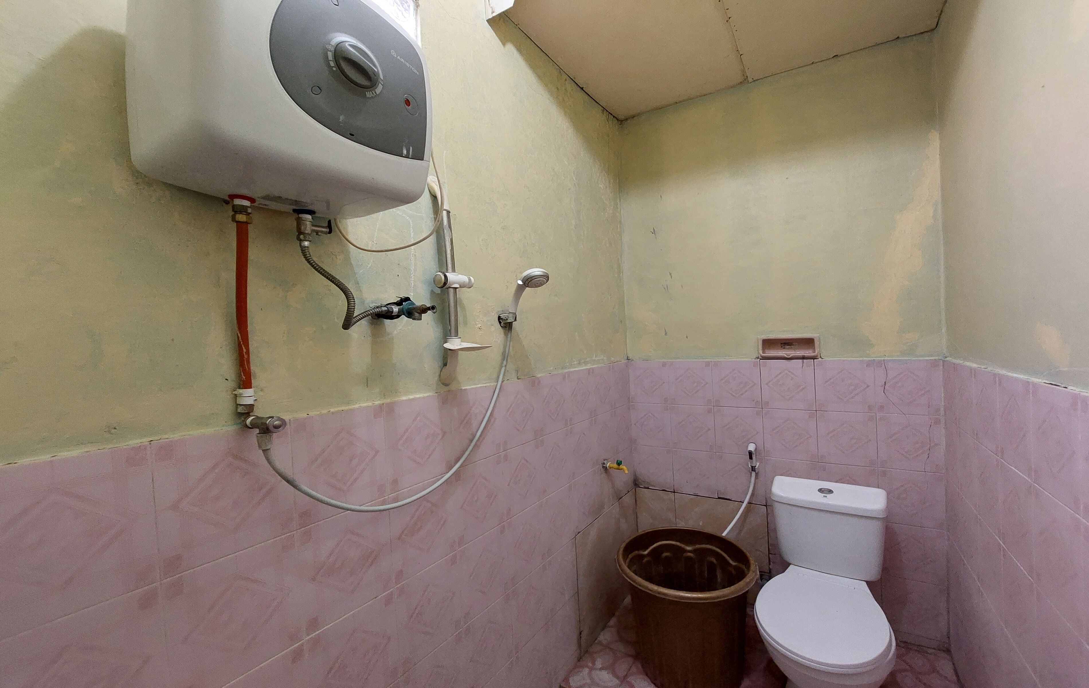 A bathroom with a toilet, a shower, and a water heater.