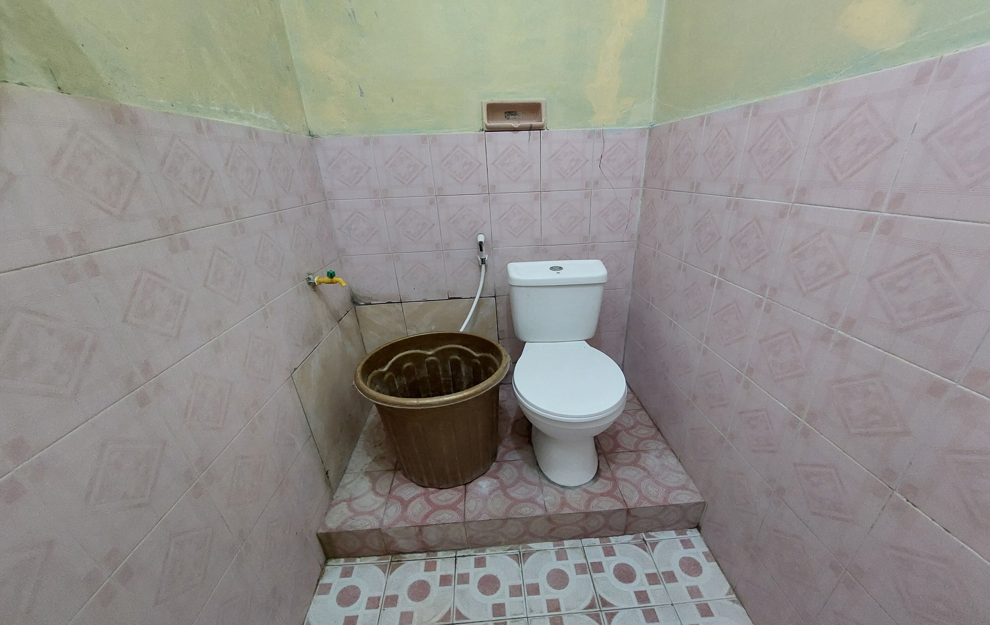 Un baño pequeño con un inodoro y un balde.